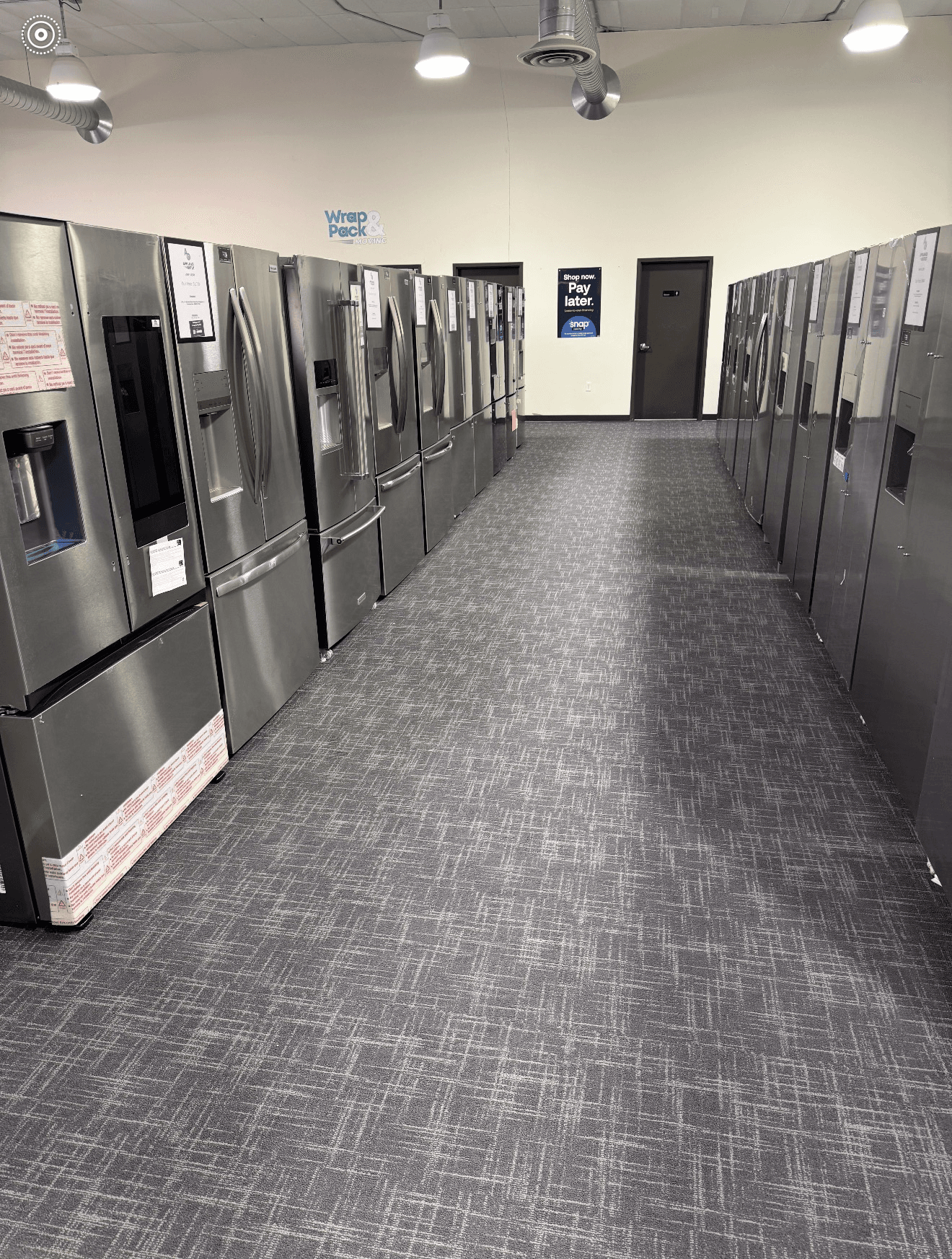 Rows of stainless steel refrigerators in the Appliance Outlet showroom